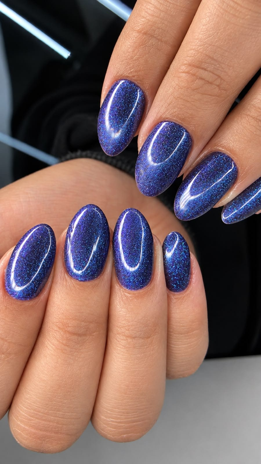Unhas amendoadas azuis com brilho e efeito olho de gato