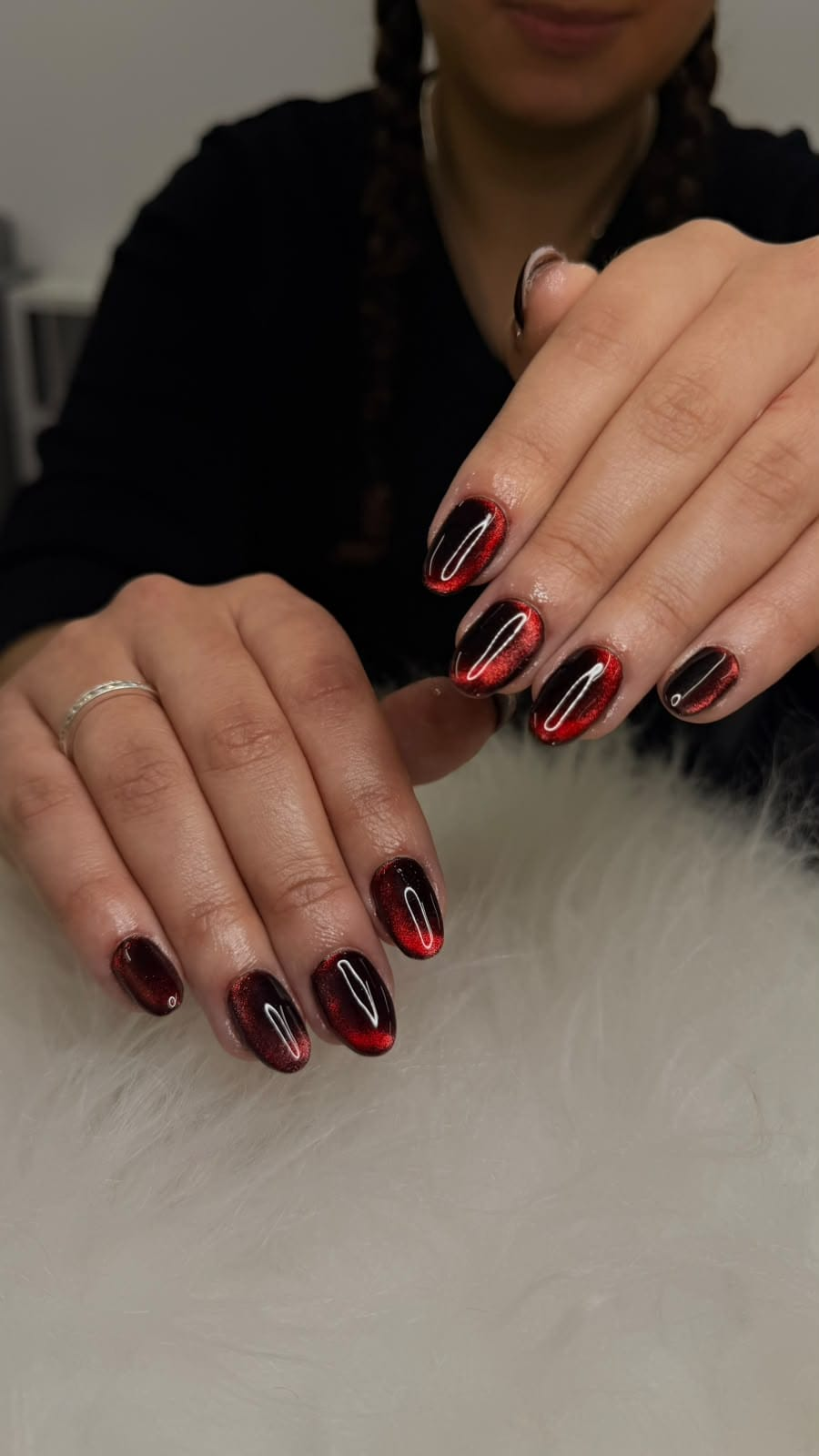 Unhas escuras com reflexos vermelhos brilhantes e efeito olho de gato